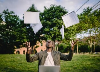 Man celebrating exam success by throwing papers into the air