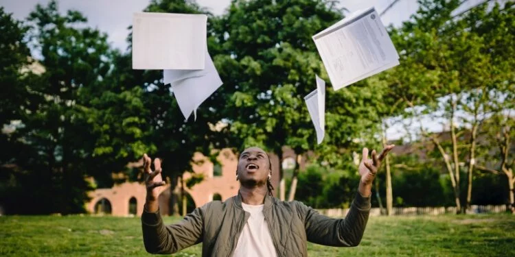Man celebrating exam success by throwing papers into the air