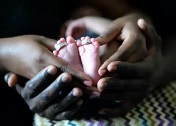 Adult hands and baby feet representing a multi-ethnic family