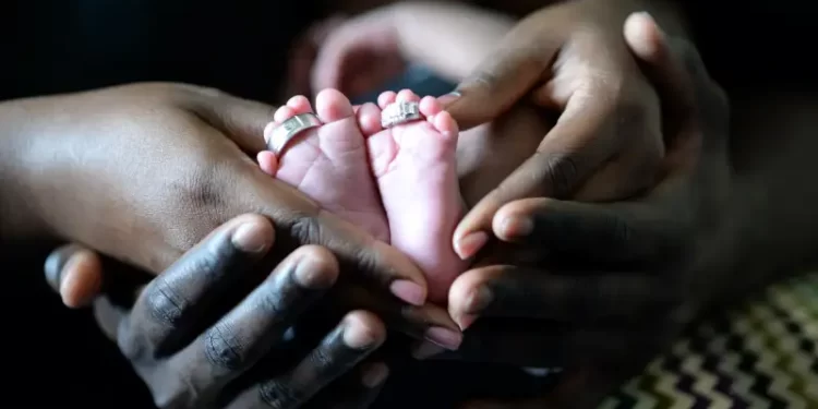 Adult hands and baby feet representing a multi-ethnic family