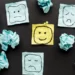 Pieces of paper with faces drawn on in various emotional states. Represents attitudes towards something.
